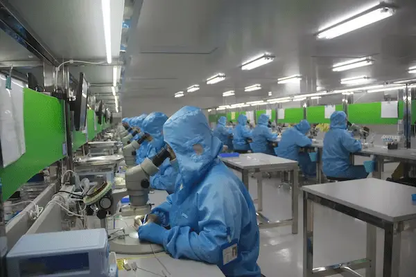scientists in blue suits looking in microscopes in a laboratory