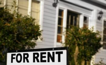A sign with the words "For Rent" outside in the front yard of a home.