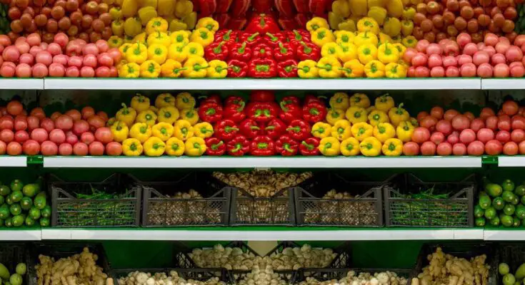 The vegetable section in a produce aisle of a small grocery store. The produce is thoughtfully showcased for better sales.