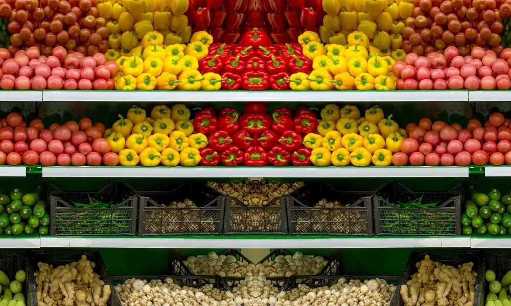The vegetable section in a produce aisle of a small grocery store. The produce is thoughtfully showcased for better sales.