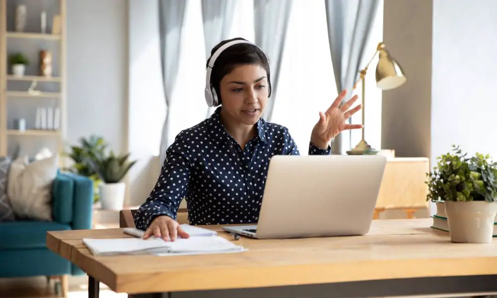 A remote worker sits at their desk in a beautifully decorated home office while hosting a virtual meeting.