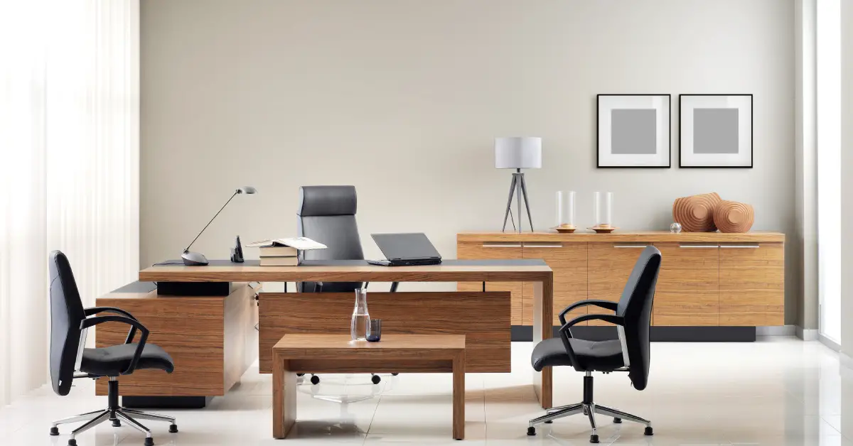 A private office with a wooden desk and coffee table. One black chair is behind the desk and two black chairs are in front of it.