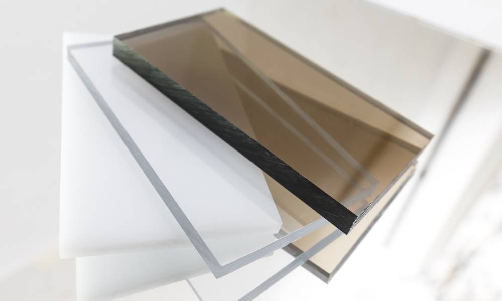 Several pieces of polycarbonate plastic lie on top of each other. Two are brown, two are white, and two are transparent.
