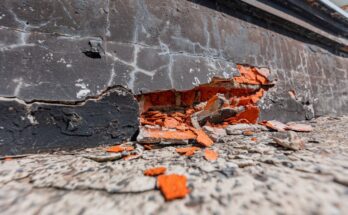 A cracked and crumbling foundation. The wall is mostly black, but the pieces coming out of it are bright orange.
