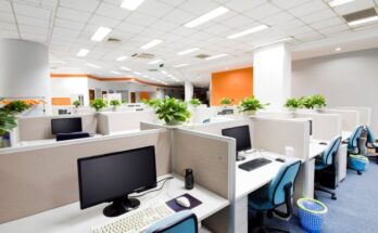 An office filled with cubicles that have low partitions. The device cords in each cubicle go through desk grommets.