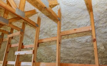 The interior of a building with bare wooden studs that have spray foam insulation between and behind them.