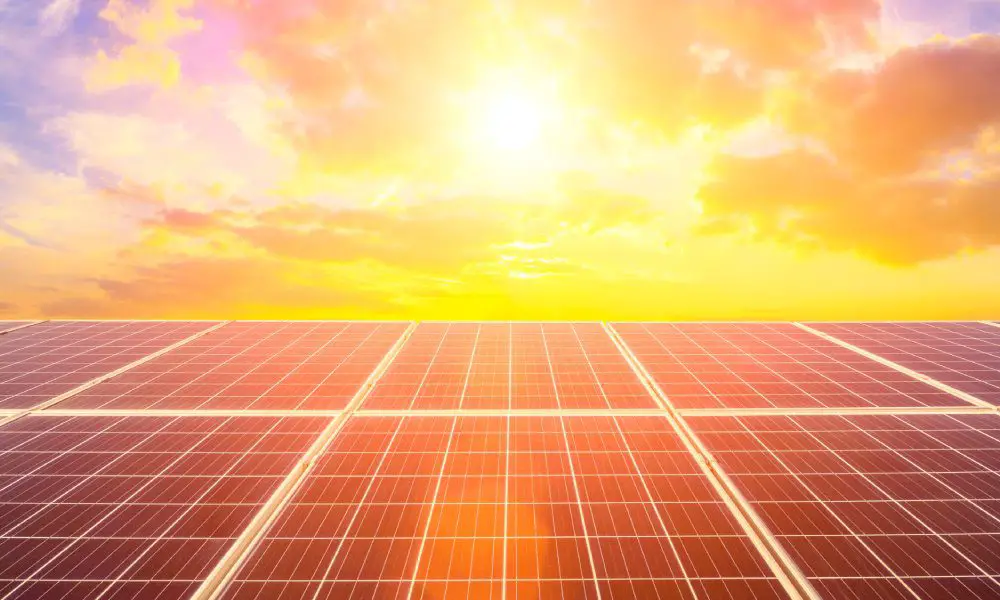 The sun shines a bright yellow and orange as it peeks through the clouds. It's charging a solar panel.