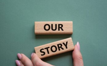 A hand adjusting a pair of wooden blocks so that they align. The wooden blocks read “our” and “story.”