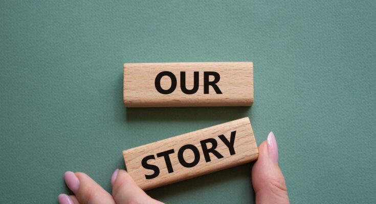 A hand adjusting a pair of wooden blocks so that they align. The wooden blocks read “our” and “story.”