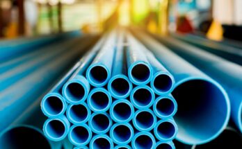 A stack of long blue plastic pipes in a warehouse. Only the mouths of the pipes are in focus.