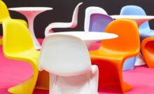 Several chairs of different colors with a contemporary design made of plastic sit around white plastic tables.