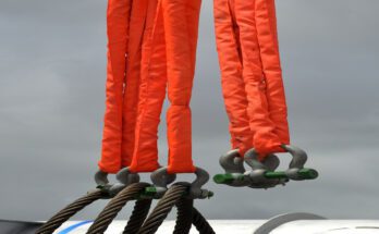 Multiple industrial cable slings are covered in a bright orange protective material. The slings hang together.