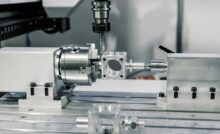 A CNC machine making a custom tool for an industrial demand. The machine is stainless steel with a computerized drill.