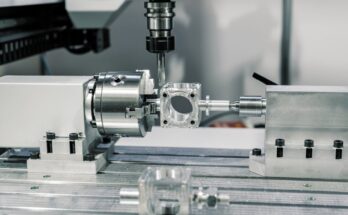 A CNC machine making a custom tool for an industrial demand. The machine is stainless steel with a computerized drill.