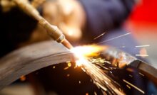 Sparks fly as the tip of an acetylene torch makes contact with a piece of metal during active cutting.
