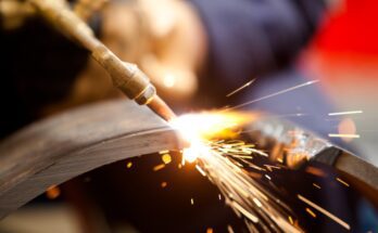 Sparks fly as the tip of an acetylene torch makes contact with a piece of metal during active cutting.