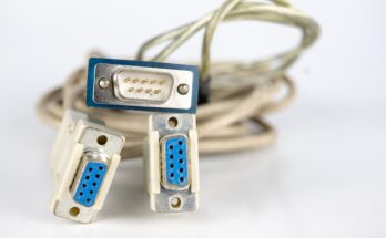 A collection of RS232 connections with blue ports and off-white cables sitting on a white surface.
