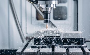 A CNC machine in the process of milling metal. There are droplets of coolant surrounding the work space.