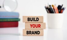 A close-up of three wooden blocks with “build,” “your,” and “brand” written on them in black and red capital letters.