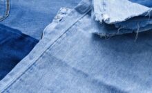 Several pairs of blue jeans flattened on top of each other. The rough, fraying hem of one pair is visible.