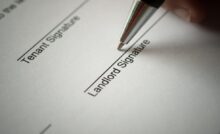 The lines for the tenant signature and the landlord signature on a rental agreement. A pen tip sits on the landlord line.