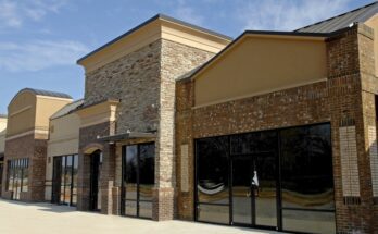 An empty commercial property with multiple connected storefronts. The windows and doors of the shops are tinted.