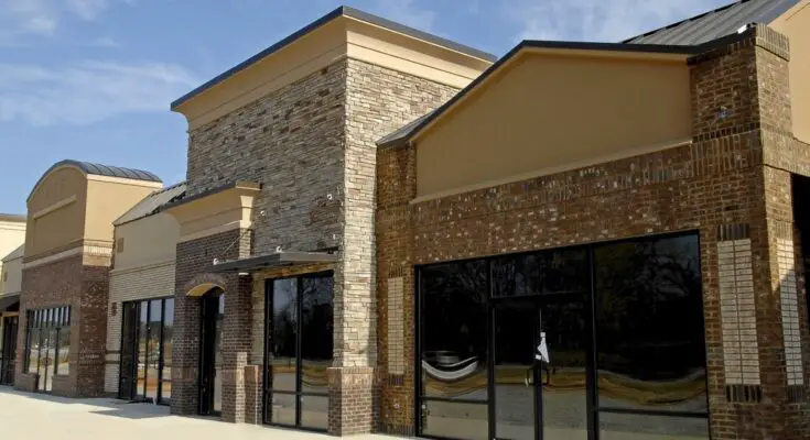 An empty commercial property with multiple connected storefronts. The windows and doors of the shops are tinted.