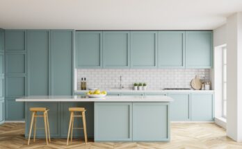 An open kitchen with white tile backsplash and pale-blue cabinets. A bowl of lemons sits on the island.