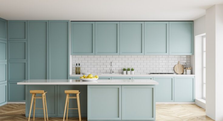An open kitchen with white tile backsplash and pale-blue cabinets. A bowl of lemons sits on the island.