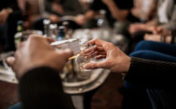 A close-up of a man's hand holding and pouring whisky from a fine alcohol sample of Japanese whisky.