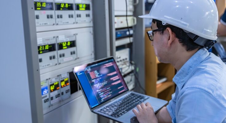 An electrical engineer is checking the voltage at the Power Distribution Cabinet in the control room.