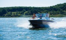 Three people, two women and one guy, are enjoying themselves on the boat as it drifts on the open water.