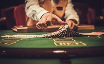 A close-up of a casino dealer at the gambling table. The dealer is shuffling cards in a line, stacked on top of each other.