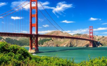 The Golden Gate Bridge in San Francisco, California. The day is sunny with some small clouds in the bright blue sky.