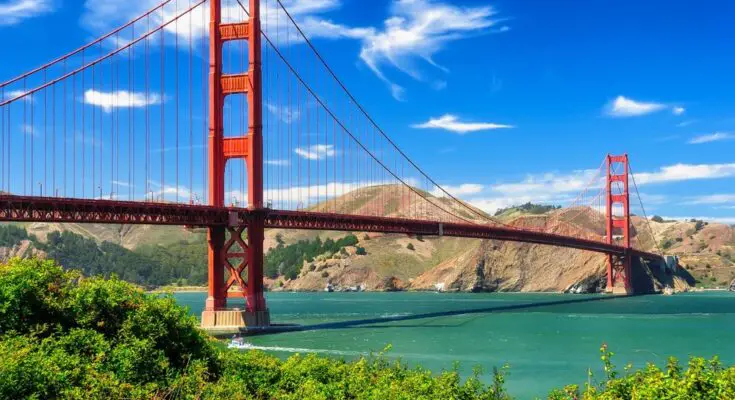 The Golden Gate Bridge in San Francisco, California. The day is sunny with some small clouds in the bright blue sky.