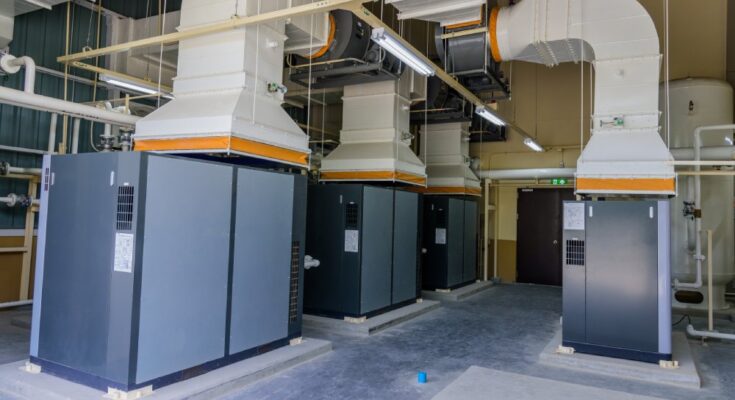 Four gray and black machines with white vents off of them as part of an air compressor system.