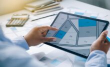 A man's point of view as he examines a map of land parcels on an electronic tablet, with some lots shaded in blue and grey.