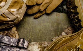 A close-up of neatly arranged military gear, such as gloves and boots, in brown and grey camouflage designs.
