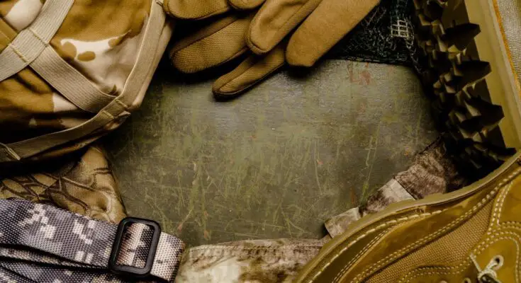A close-up of neatly arranged military gear, such as gloves and boots, in brown and grey camouflage designs.