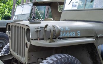 A close-up view of the front end of a restored 1941 Willys MB military Jeep. The Jeep is painted its authentic color.