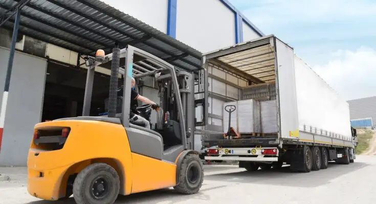 A forklift drives to the back of a semitruck to unload the cargo that was shipped across the country.
