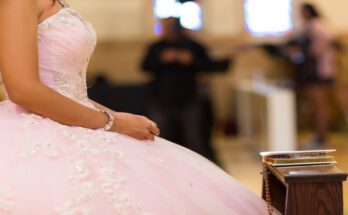 An extreme close-up of a young woman on her quinceañera day, wearing a pink and jeweled ball-gown dress.