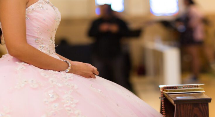 An extreme close-up of a young woman on her quinceañera day, wearing a pink and jeweled ball-gown dress.