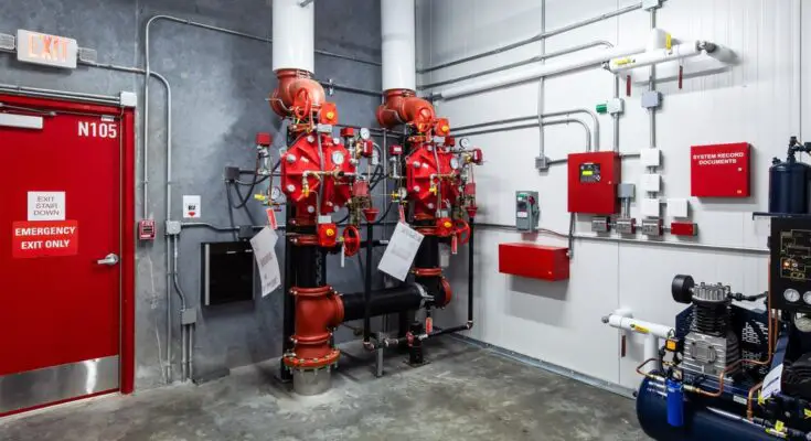 A bright red indoor water pump for a fire protection system in a warehouse or factory facility for safety.