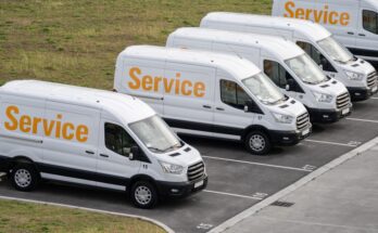 Several company vans sit in parking spaces along side each other. Their sides read "Service" in yellow letters.