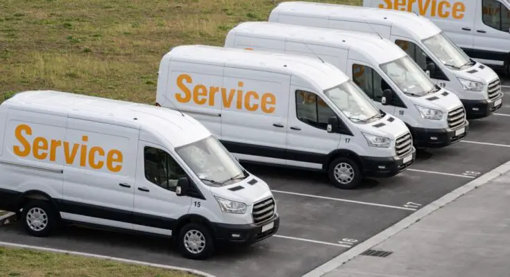 Several company vans sit in parking spaces along side each other. Their sides read "Service" in yellow letters.