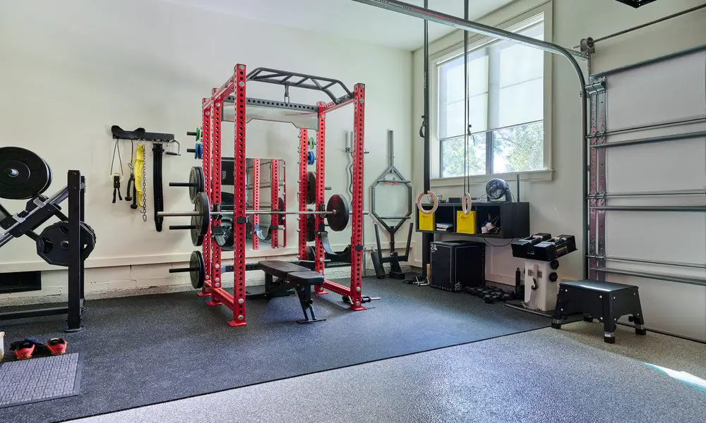 Several pieces of workout equipment are in the corner of a room. There is a window to the right of frame.