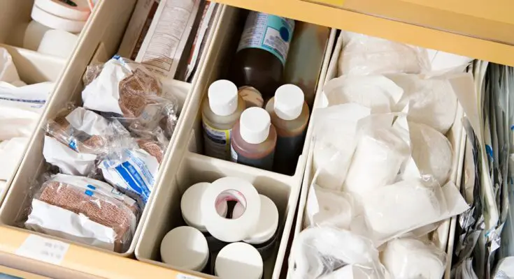A drawer with neatly organized containers and dividers containing medical supplies, including gauze, tape, and bandages.