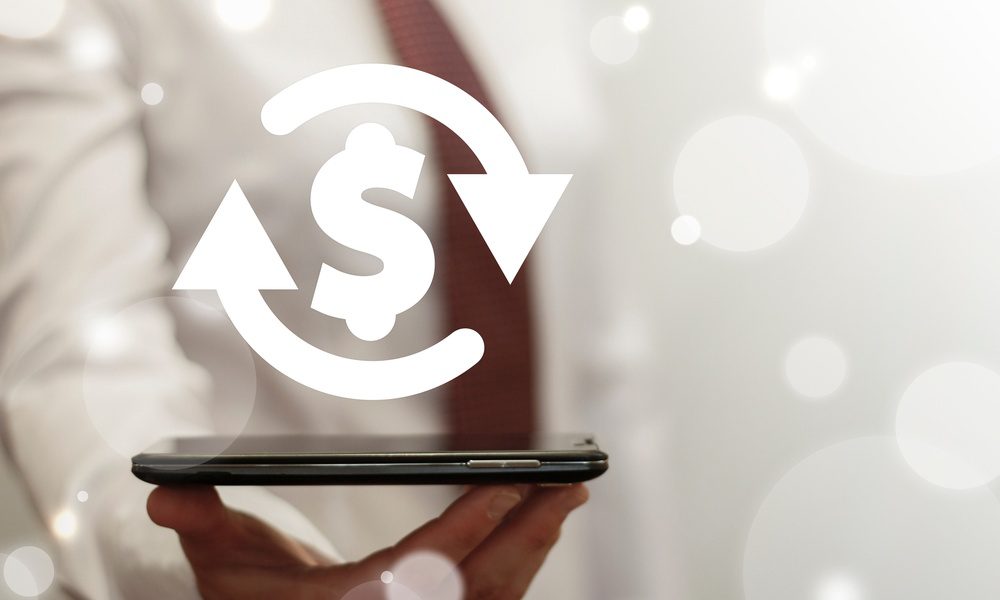 A person holding out a smartphone that has a dollar symbol with circular arrows going around it floating off the screen.
