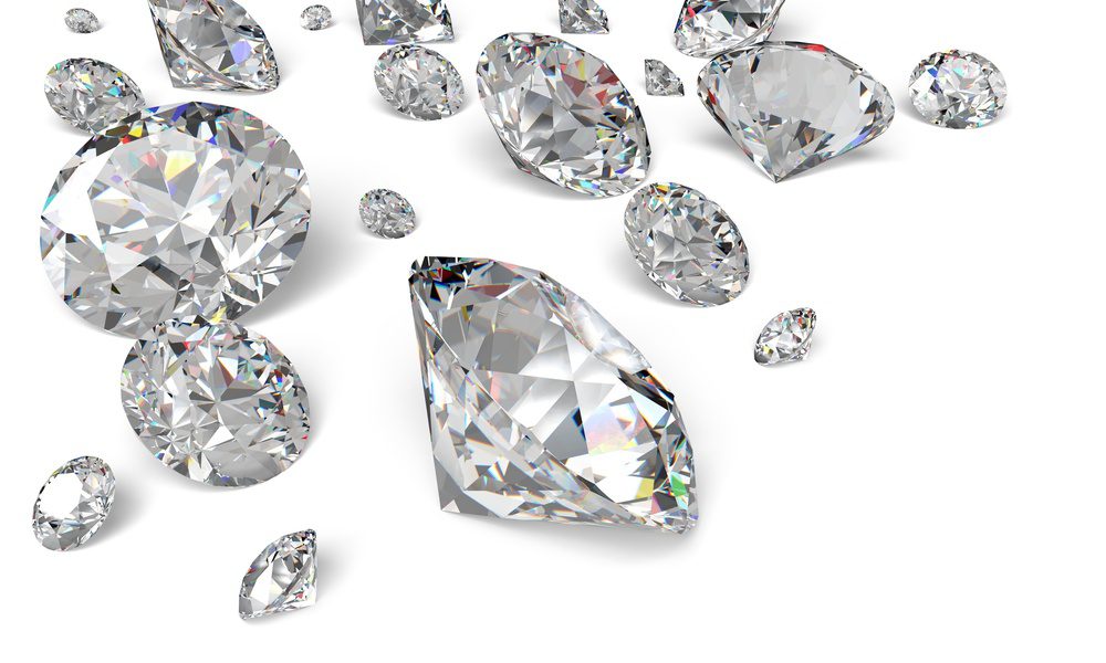 Assorted loose diamonds in round and pear-shaped cuts sparkle with colorful reflections against a white background.